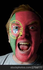 Low key portrait of an angry man whose face is painted in colors of portugal flag