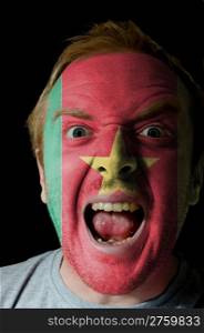 Low key portrait of an angry man whose face is painted in colors of cameroon flag