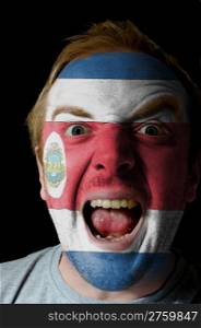 Low key portrait of an angry man whose face is painted in colors of costarican flag
