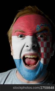 Low key portrait of an angry man whose face is painted in colors of croatian flag