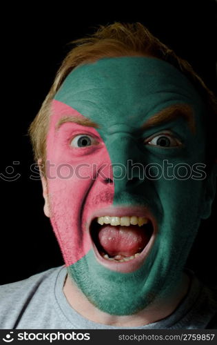 Low key portrait of an angry man whose face is painted in colors of bangladesh flag