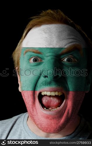 Low key portrait of an angry man whose face is painted in colors of bulgarian flag
