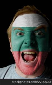 Low key portrait of an angry man whose face is painted in colors of bulgarian flag