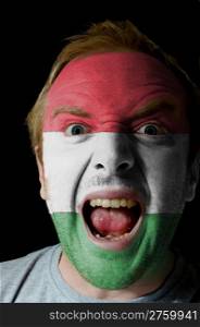 Low key portrait of an angry man whose face is painted in colors of hungary flag