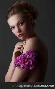low key portrait of young blond glamor woman with some carnation purple flower around one arm