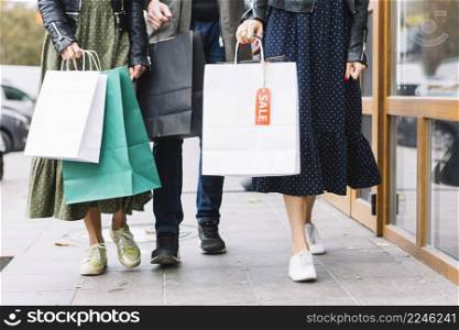 low section friends walking sidewalk with colorful shopping bags