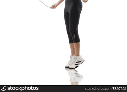 Low section of a woman skipping over white background