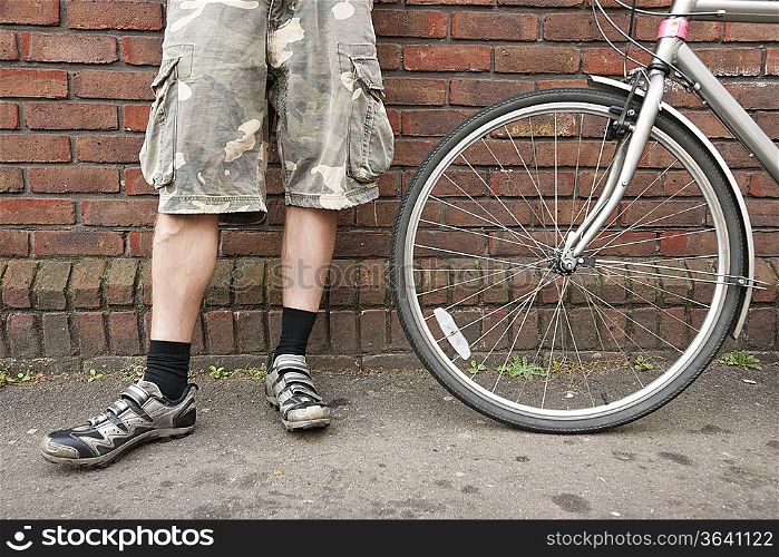 Low section of biker standing with bicycle