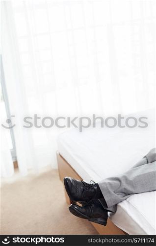 Low section of businessman lying in hotel room