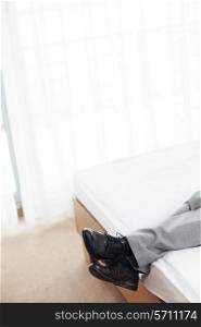 Low section of businessman lying in hotel room