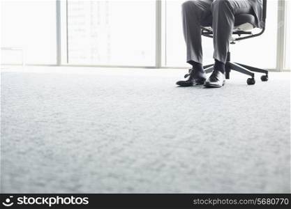 Low section of businessman sitting on office chair