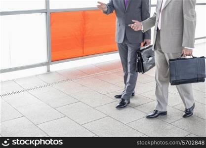 Low section of businessmen communicating while walking in railroad station