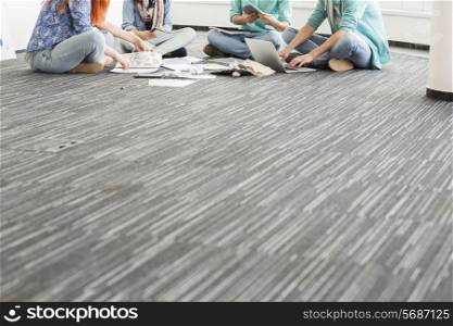 Low section of businesspeople working on floor in creative office