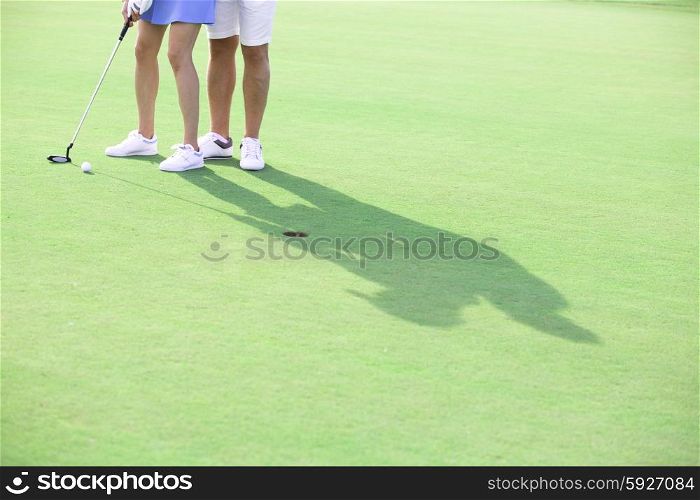 Low section of couple playing golf at course