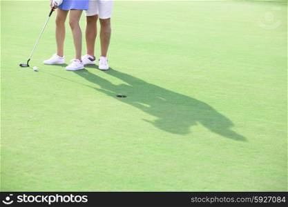 Low section of couple playing golf at course