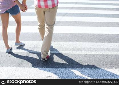 Low section of couple walking on crosswalk