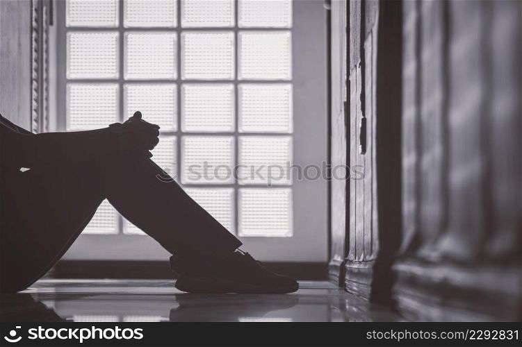 Low section of depressed woman sitting alone with hugging her knees on corridor at apartment in low key and monochrome style, mental health concept