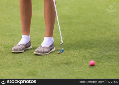 Low section of female golf player ready to hit the ball
