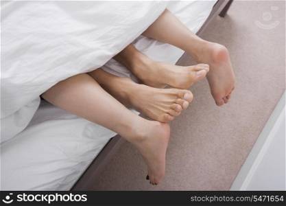 Low section of intimate couple in bed
