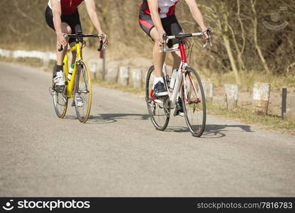 Low section of male athletes riding bicycles on a country road