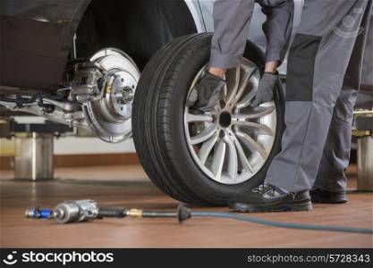 Low section of male mechanic repairing car&rsquo;s tire in repair shop