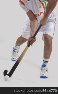 Low section of man playing hockey isolated over gray background