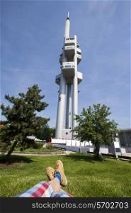 Low section of man relaxing in front of Zizkov Television Tower in Prague, Czech Republic