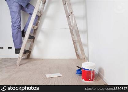Low section of man&rsquo;s legs climbing wooden ladder