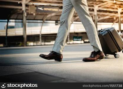 Low Section of Passenger Businessman Walking with Suitcase at the Entrance Walkway in Airport. Focus on Luggage. Low Angle View