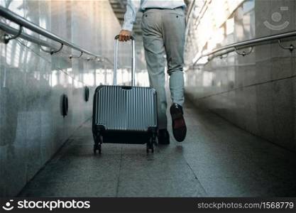 Low Section of Passenger Businessman Walking with Suitcase at the Walkway in Airport. Focus on Luggage. Low Angle View