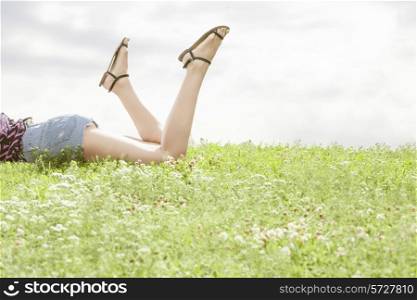 Low section of woman lying on grass against sky