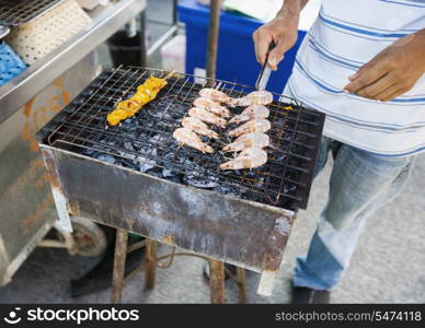 Low section of young man cooking prawns on barbecue; Koh Pha Ngan; Thailand