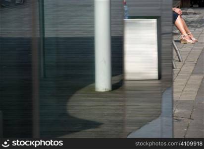 Low section of young woman sitting in bus stop, Ireland, Cork