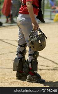 Low section view of a baseball catcher holding a helmet