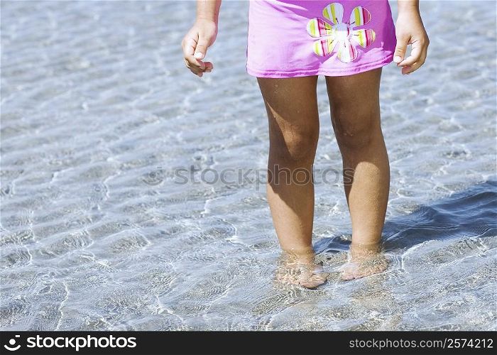 Low section view of a girl standing in water on the beach