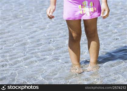 Low section view of a girl standing in water on the beach