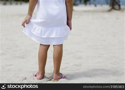 Low section view of a girl standing on the beach