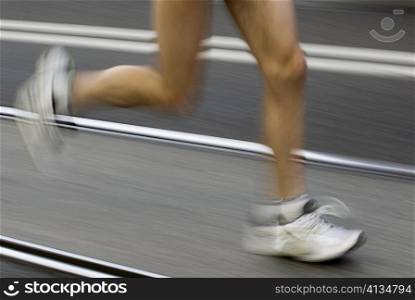 Low section view of a male athlete running on a running track