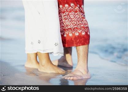 Low section view of a man and a woman standing on the beach