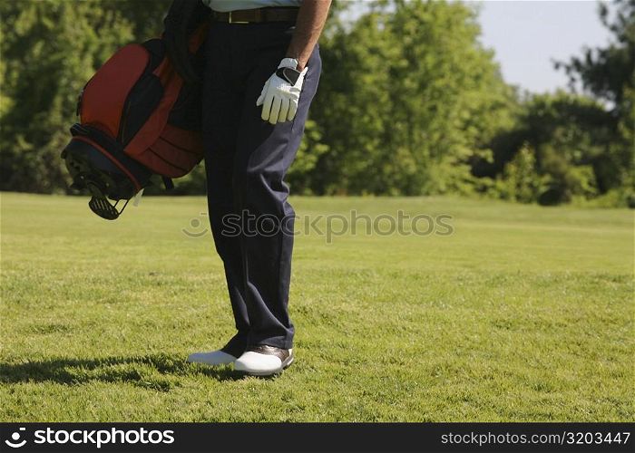 Low section view of a man carrying a golf bag