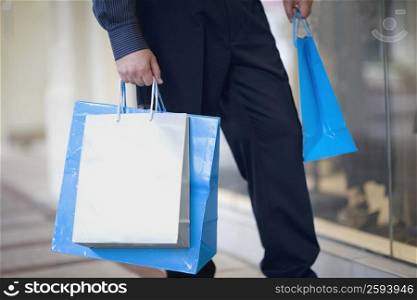 Low section view of a man carrying shopping bags