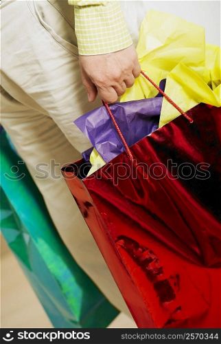 Low section view of a man holding shopping bags