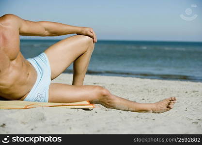 Low section view of a man lying on the beach