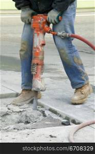 Low section view of a man operating a jackhammer on the road
