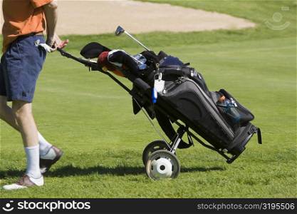 Low section view of a man pulling a golf bag