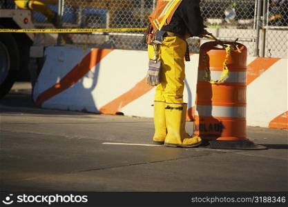 Low section view of a manual worker standing near a garbage bin