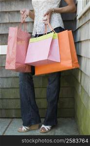 Low section view of a mature woman holding shopping bags