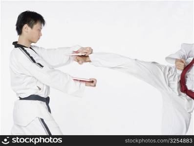 Low section view of a mid adult man practicing kickboxing with a young man