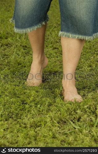 Low section view of a mid adult man walking on the grass