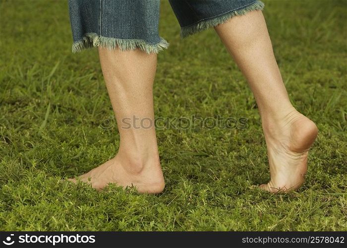 Low section view of a mid adult man walking on the grass